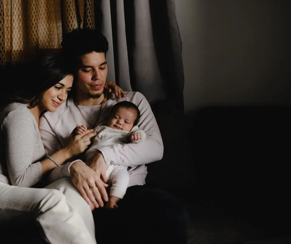 A mother and father cradling their newborn on a sofa